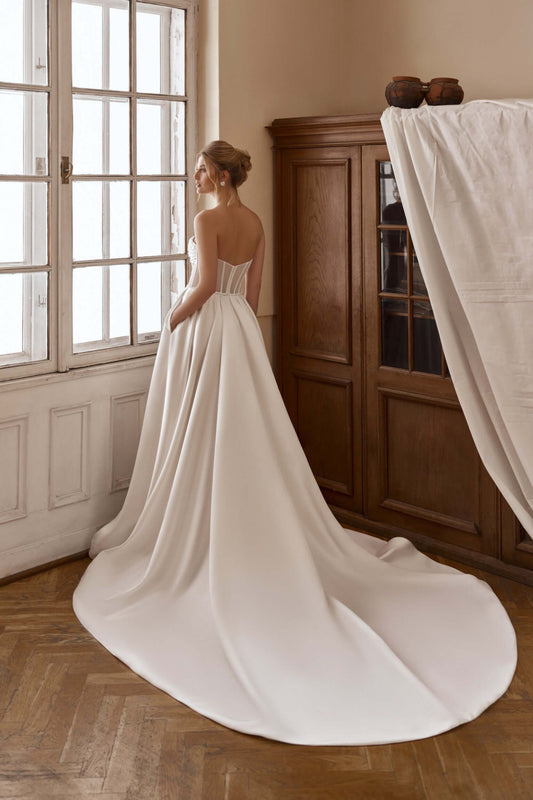 braut im schlichten brautkleid mit langer schleppe und beinschlitz